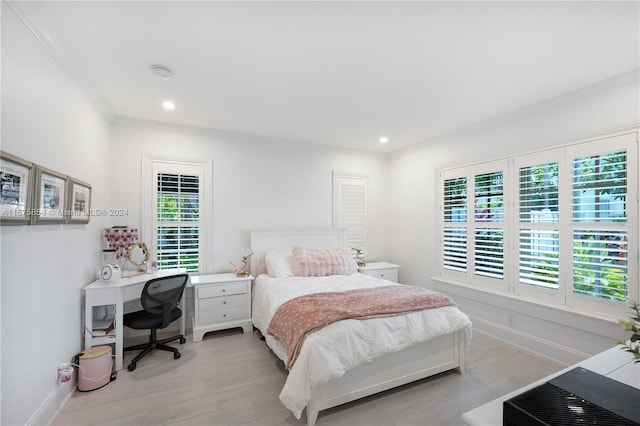 bedroom featuring ornamental molding, light wood-type flooring, and multiple windows