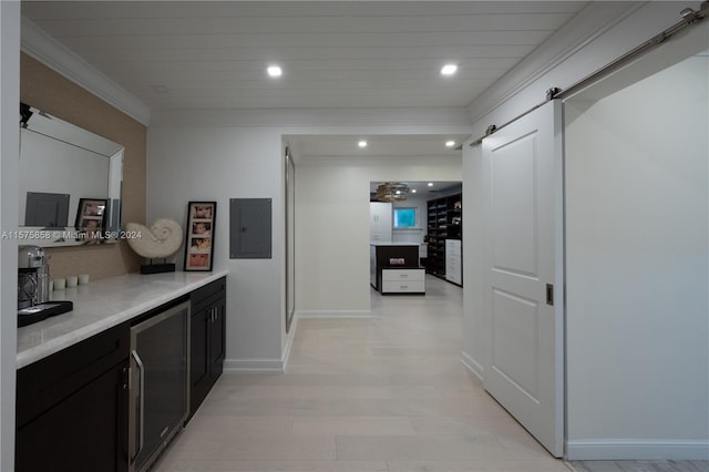 corridor featuring light hardwood / wood-style flooring, crown molding, and a barn door