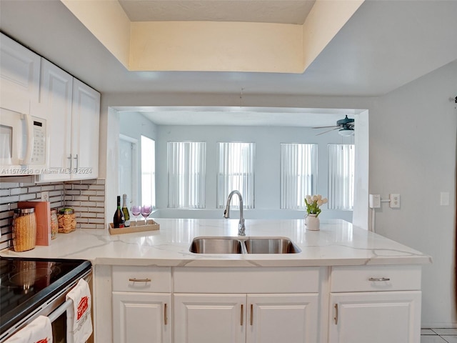 kitchen with tasteful backsplash, white cabinets, ceiling fan, and sink