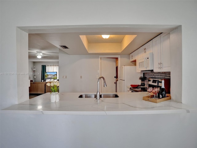 kitchen featuring white appliances, white cabinets, sink, light stone counters, and ceiling fan