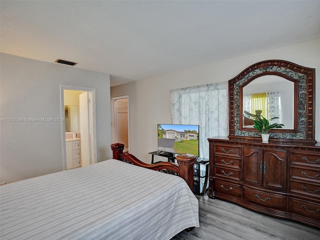 bedroom featuring light hardwood / wood-style flooring and connected bathroom