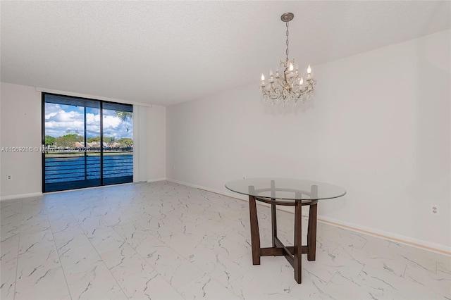 unfurnished dining area with marble finish floor, a notable chandelier, a textured ceiling, and baseboards