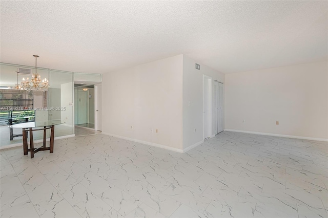 spare room with a textured ceiling, marble finish floor, visible vents, and baseboards