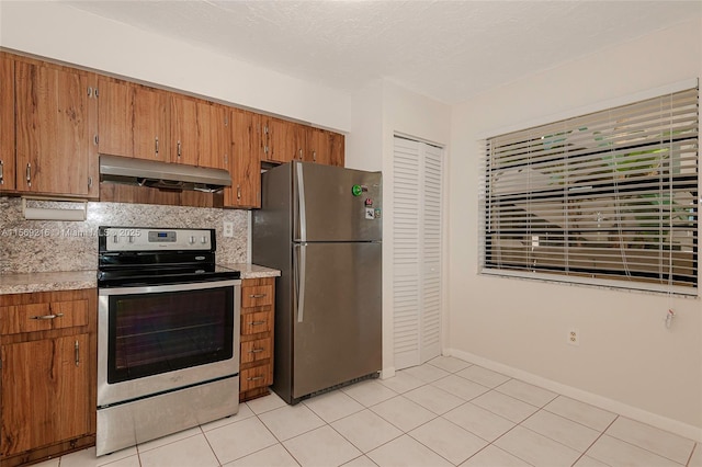 kitchen featuring appliances with stainless steel finishes, brown cabinetry, and under cabinet range hood