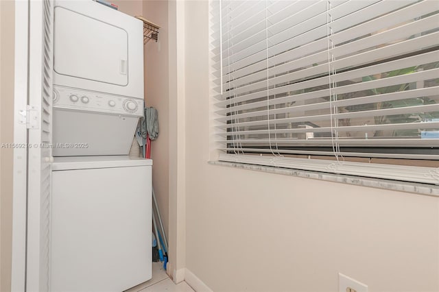 laundry room featuring baseboards, laundry area, tile patterned floors, and stacked washer / drying machine