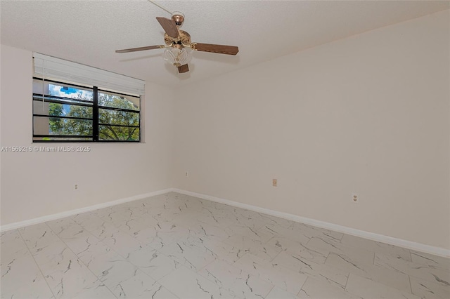 empty room featuring a ceiling fan, marble finish floor, a textured ceiling, and baseboards