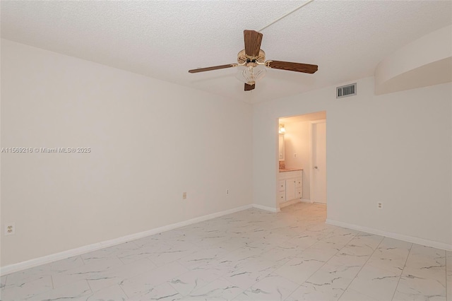 unfurnished room with marble finish floor, baseboards, visible vents, and a textured ceiling