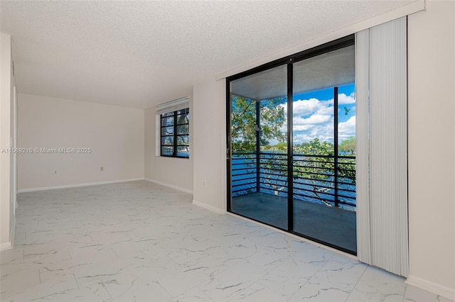 empty room featuring marble finish floor, expansive windows, baseboards, and a textured ceiling