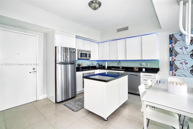 kitchen with appliances with stainless steel finishes, tasteful backsplash, a kitchen island, and white cabinets