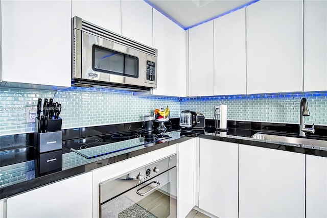 kitchen featuring appliances with stainless steel finishes, sink, backsplash, and white cabinetry