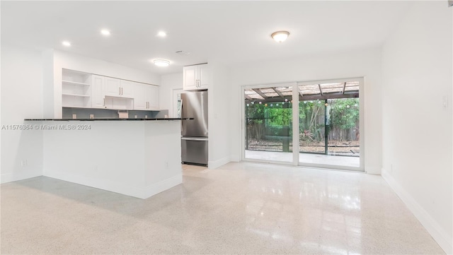 kitchen featuring kitchen peninsula, stainless steel fridge, and white cabinetry