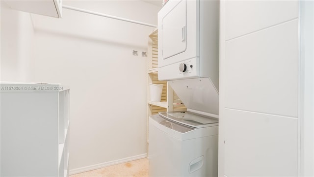 laundry room featuring stacked washer / dryer and light carpet