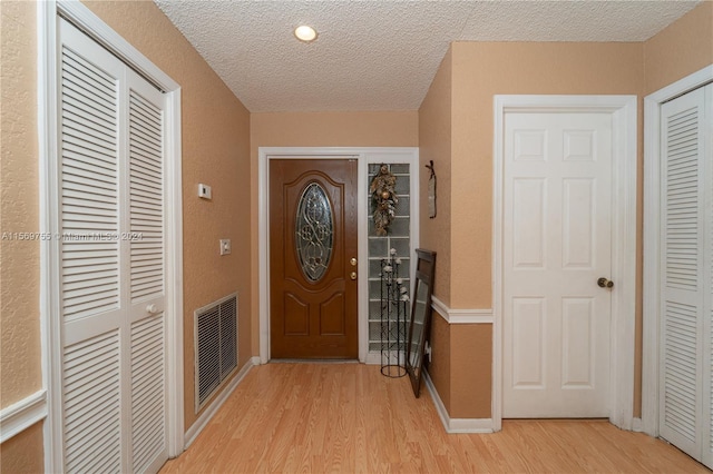 entryway featuring a textured ceiling and light hardwood / wood-style flooring