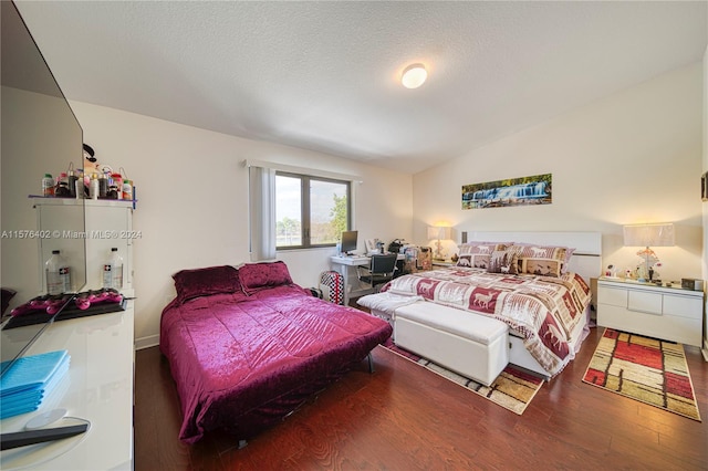 bedroom featuring a textured ceiling, hardwood / wood-style floors, and vaulted ceiling