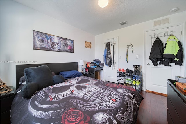 bedroom with a closet, a textured ceiling, and dark hardwood / wood-style flooring