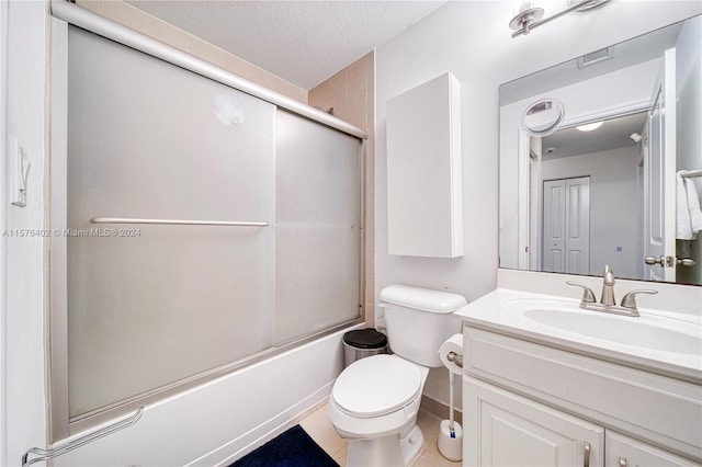 full bathroom featuring tile floors, large vanity, bath / shower combo with glass door, toilet, and a textured ceiling