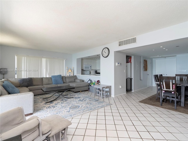 living room with visible vents, a textured ceiling, and light tile patterned floors