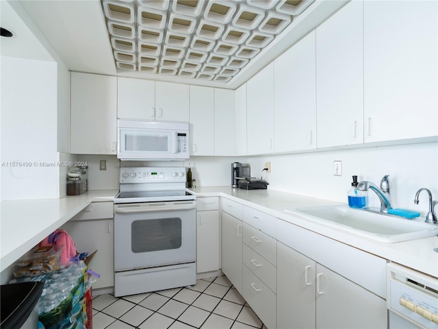 kitchen featuring white appliances, light countertops, a sink, and white cabinetry