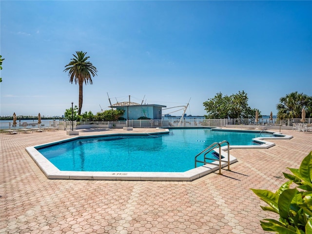 community pool with a patio area and fence