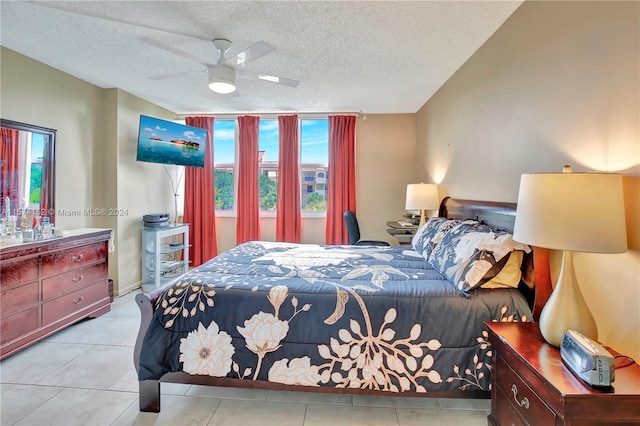 tiled bedroom featuring a textured ceiling, ceiling fan, and multiple windows