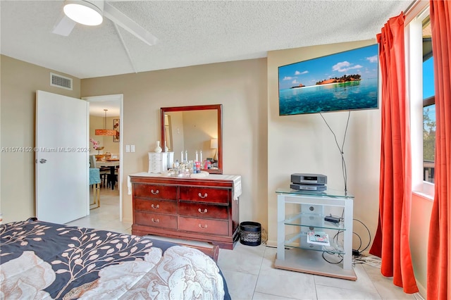 tiled bedroom featuring ceiling fan and a textured ceiling