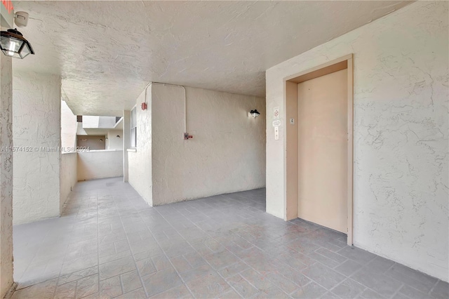 tiled empty room featuring a textured ceiling