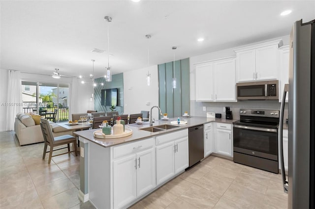 kitchen with appliances with stainless steel finishes, ceiling fan, sink, kitchen peninsula, and pendant lighting