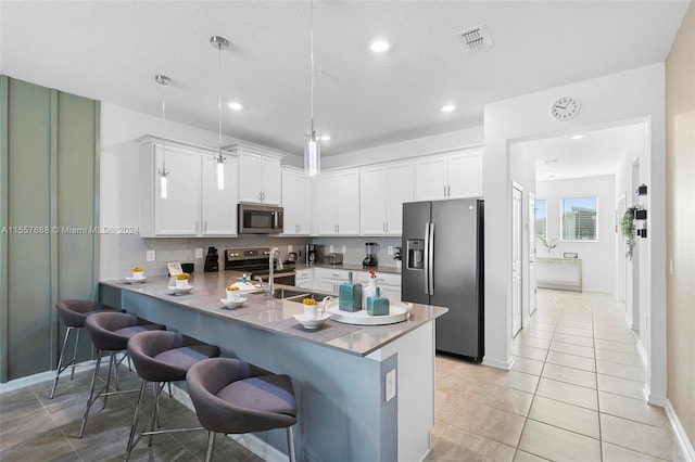 kitchen featuring hanging light fixtures, white cabinets, light tile flooring, stainless steel appliances, and sink