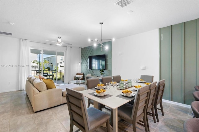 tiled dining room with ceiling fan with notable chandelier