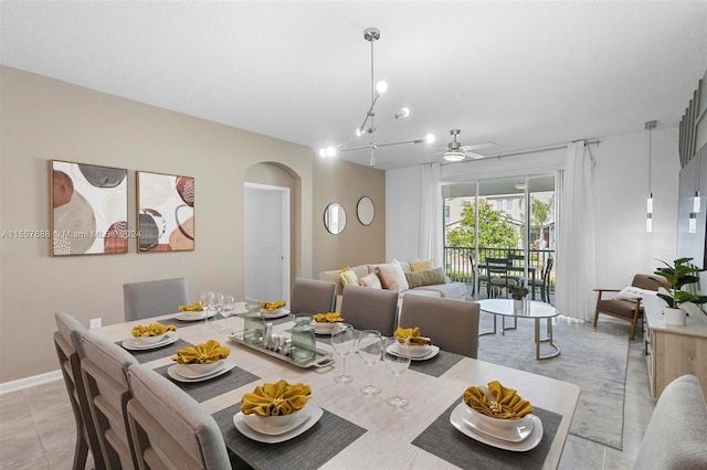 tiled dining area featuring ceiling fan with notable chandelier