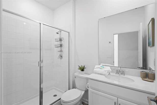 bathroom featuring a shower with shower door, vanity, and toilet