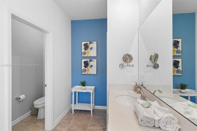 bathroom with toilet, tile flooring, vanity, and a textured ceiling