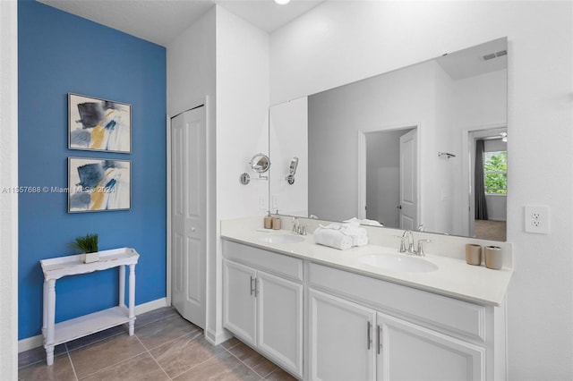 bathroom featuring vanity with extensive cabinet space, tile floors, and double sink