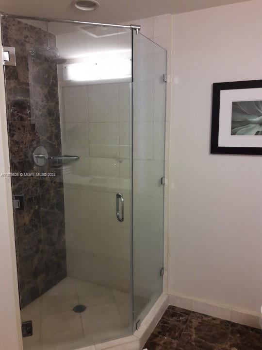 bathroom featuring an enclosed shower and tile flooring