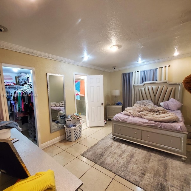 tiled bedroom featuring a walk in closet, a closet, ornamental molding, and a textured ceiling