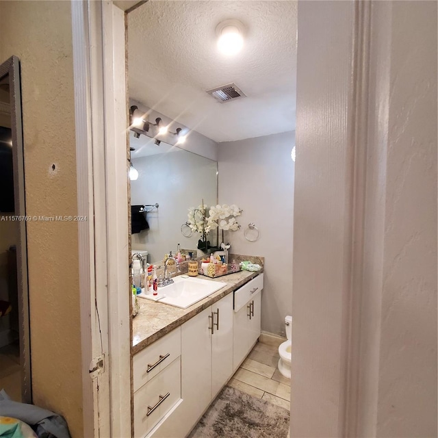 bathroom with tile floors, a textured ceiling, toilet, and vanity