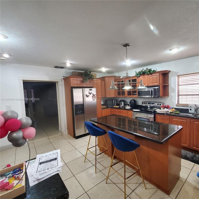 kitchen with a breakfast bar area, stainless steel appliances, a kitchen island, and light tile floors