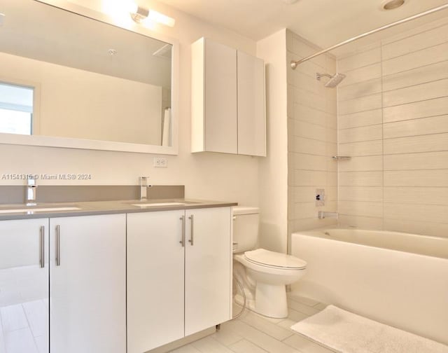 full bathroom featuring tile floors, vanity, tiled shower / bath combo, and toilet