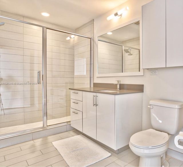 bathroom with tile flooring, vanity, toilet, and a shower with shower door