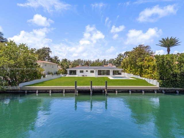 rear view of house with a water view, fence, an outdoor pool, and a yard