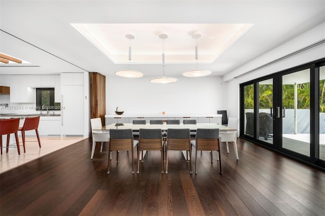 dining area featuring a raised ceiling, dark wood finished floors, and french doors