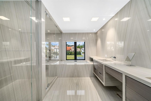 full bathroom with double vanity, a garden tub, a shower stall, and a sink