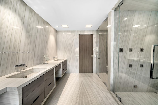 bathroom featuring double vanity, a stall shower, a sink, and tile walls