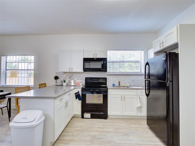 kitchen with plenty of natural light, kitchen peninsula, light hardwood / wood-style flooring, and black appliances