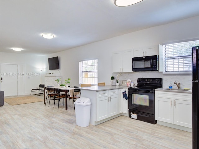 kitchen with white cabinetry, kitchen peninsula, light hardwood / wood-style flooring, and black appliances