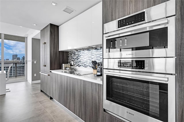 kitchen featuring tasteful backsplash, white cabinets, light tile flooring, electric cooktop, and stainless steel double oven