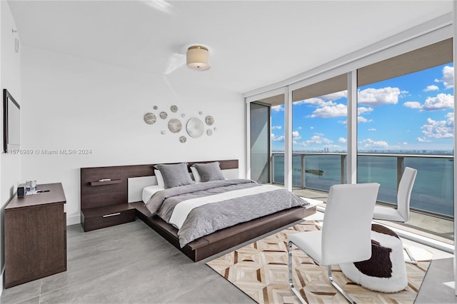 bedroom featuring floor to ceiling windows, a water view, and access to outside