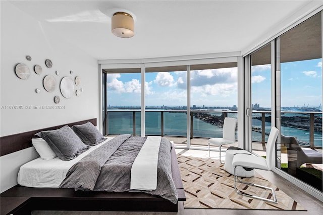 bedroom featuring a water view, expansive windows, and access to outside