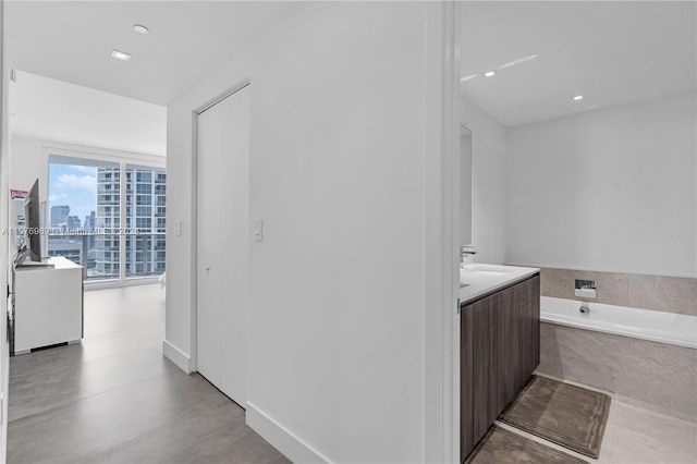 bathroom featuring tile flooring, vanity, and tiled bath