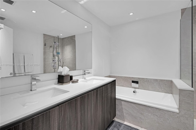 bathroom with tile floors, independent shower and bath, and double sink vanity